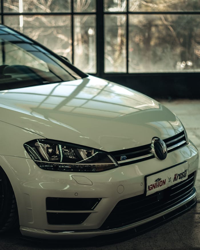A sleek white Volkswagen Golf showcased in a contemporary indoor showroom, emphasizing its stylish design.